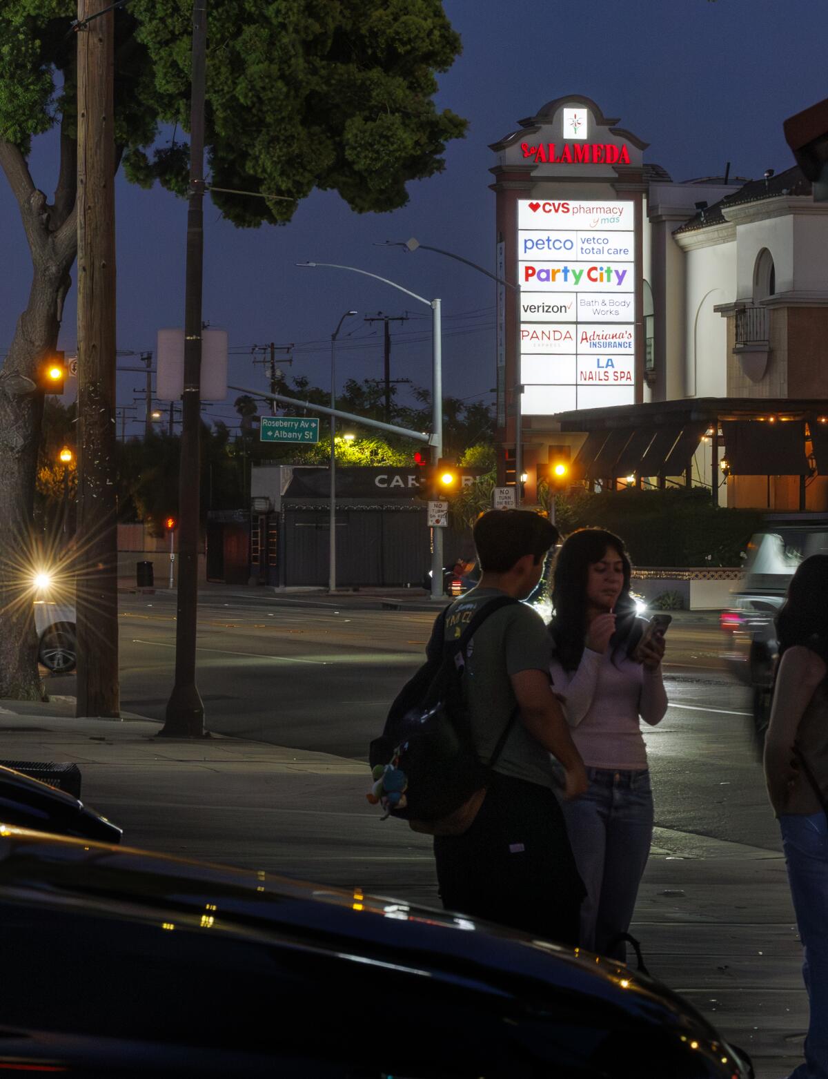 Les résidents attendent à un arrêt de bus en face de la Plaza La Alameda à Walnut Park.