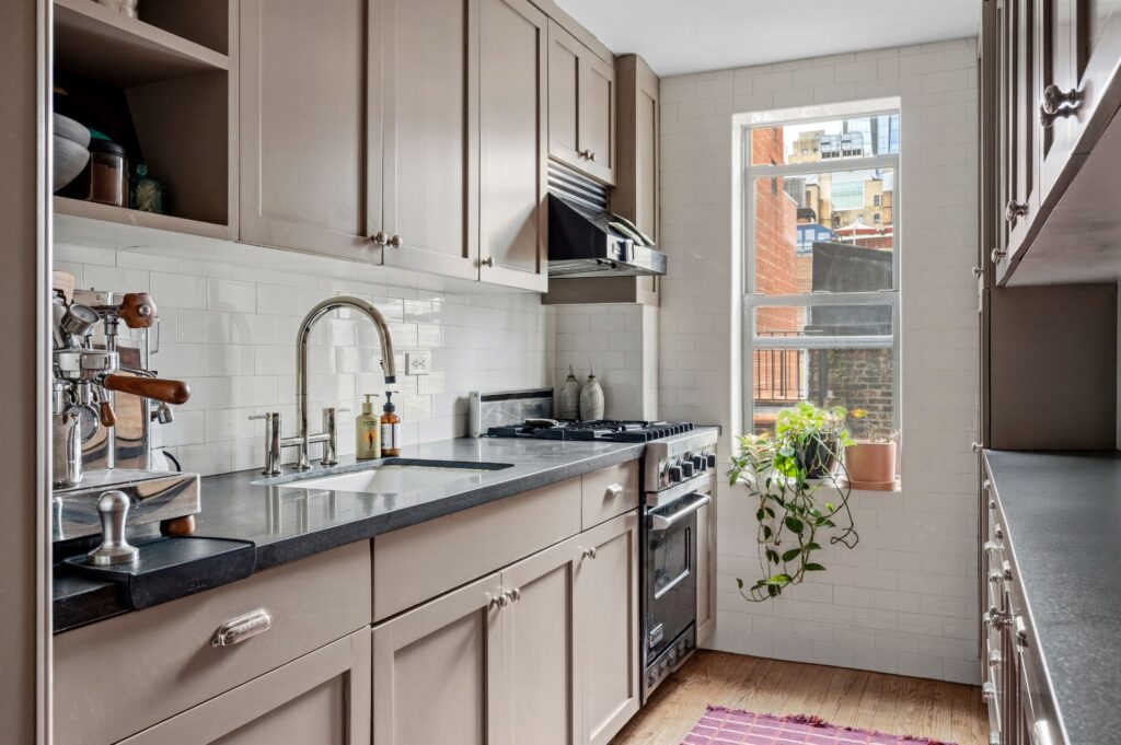 Cuisine d'appartement d'avant-guerre rénovée au 140 East 28th Street à Manhattan, dotée d'appareils électroménagers haut de gamme, d'une cuisinière à gaz et d'une fenêtre avec vue sur la ville.