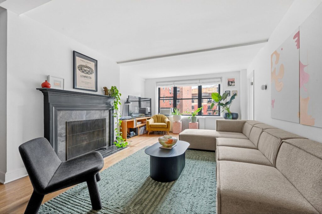 Salon d'un appartement d'une chambre d'avant-guerre ensoleillé avec une cheminée décorative et une vue dégagée sur la ville au 140 East 28th Street à Kips Bay, Manhattan.