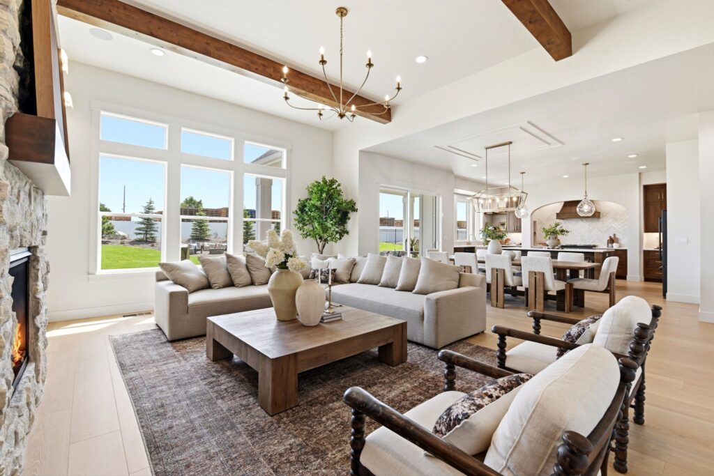 Salon et salle à manger à aire ouverte avec de larges planchers en chêne, des poutres apparentes et un grand lustre au 7042 E Chicken Hawk Loop à Nampa, Idaho.