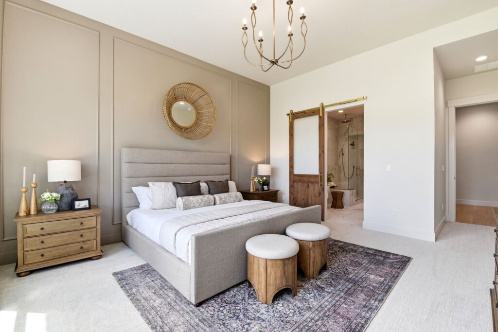 Chambre principale primée de la mission espagnole au 7042 E Chicken Hawk Loop à Nampa, Idaho, avec un mur d'accent beige chaud, une porte de grange en bois et une vue sur la salle de bain attenante.
