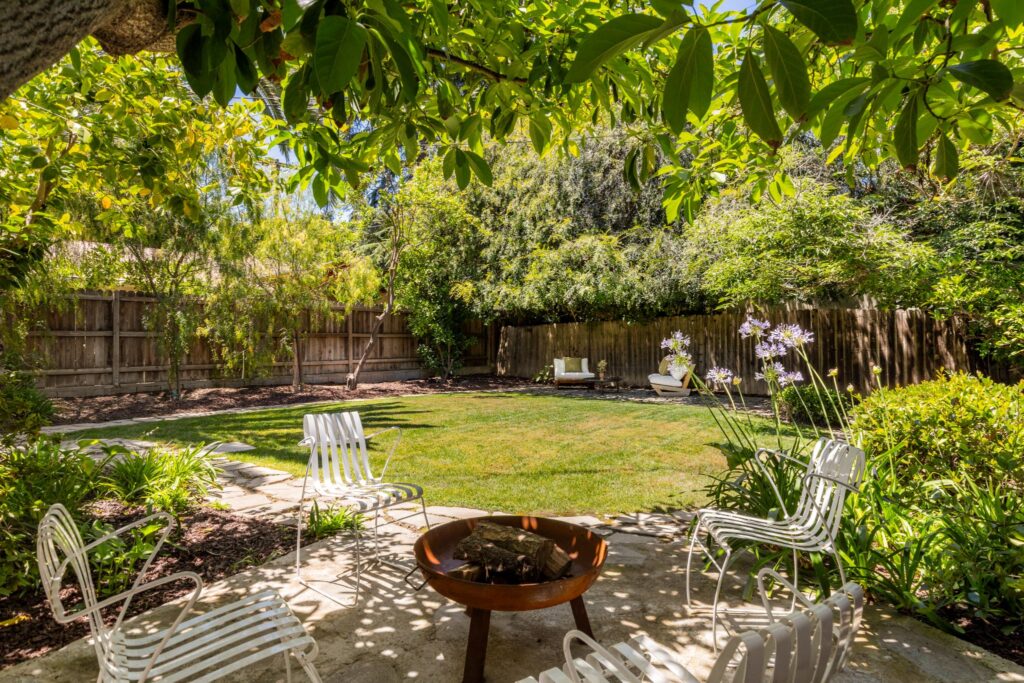 Cour clôturée avec pelouse verte, un foyer en pierre et des arbres fruitiers matures au 22051 Celes Street à Woodland Hills, en Californie.
