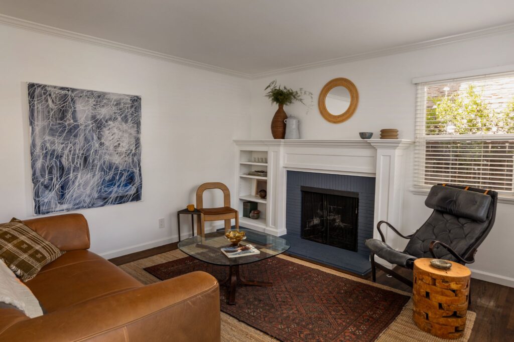 Salon moderne rénové du milieu du siècle avec une cheminée en brique, un canapé en cuir et du parquet sombre au 22051 Celes Street à Woodland Hills, en Californie.