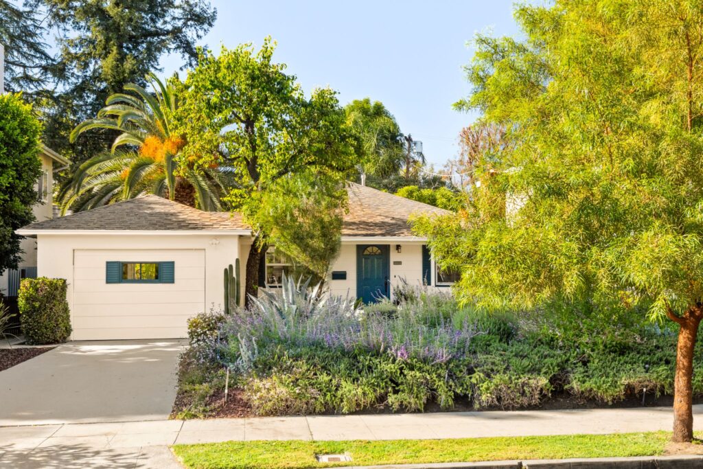 Extérieur d'une maison unifamiliale avec un aménagement paysager indigène mature, un palmier et un porche accueillant au 22051 Celes Street à Woodland Hills, en Californie.