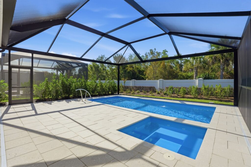 Piscine d'eau salée personnalisée et spa intégré entourés d'une cage de véranda avec baie vitrée au 9194 Cayman Drive à Azure à Hacienda Lakes, Naples, Floride.