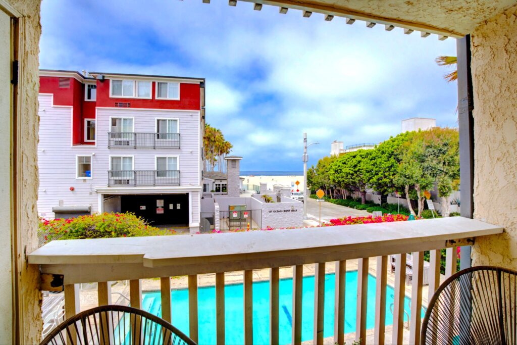 Vue sur le balcon du patio de l'appartement Breezy donnant sur une piscine communautaire chauffée et un aperçu de Venice Beach au 22 Navy Street à Venice, en Californie.