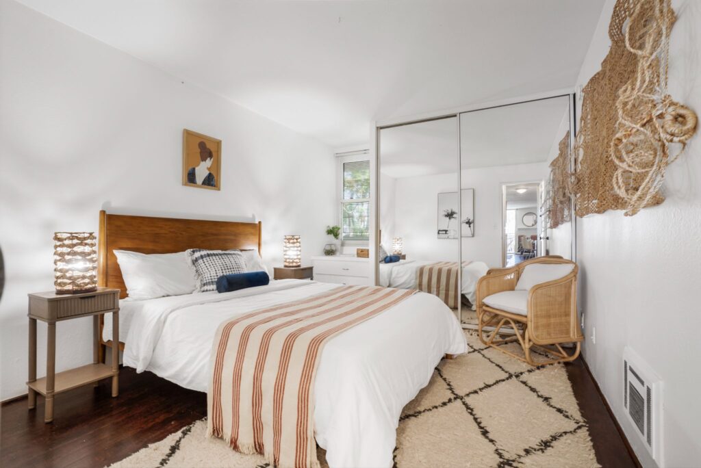 Chambre de style bohème avec parquet en bois foncé, grandes portes de placard en miroir et décorations tissées au 22 Navy Street à Venice, en Californie.